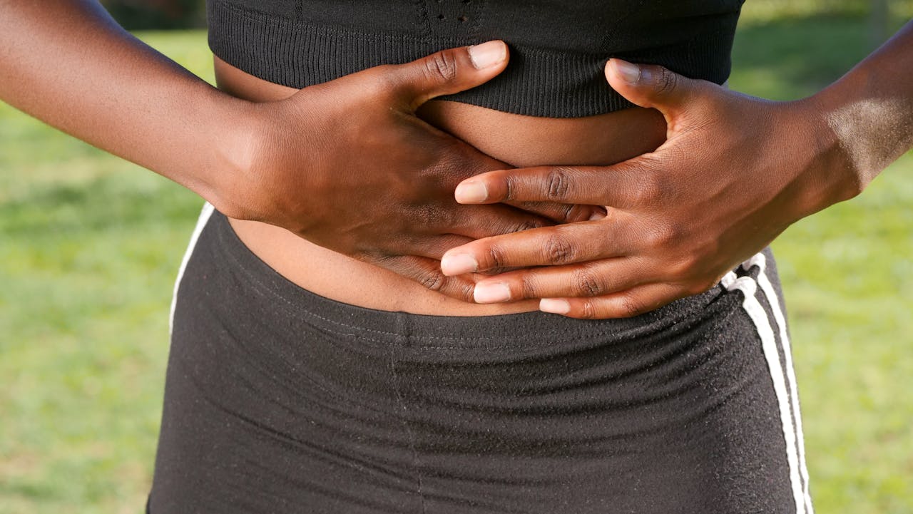 Woman holding her stomach while experiencing digestive discomfort linked to SIBO symptoms